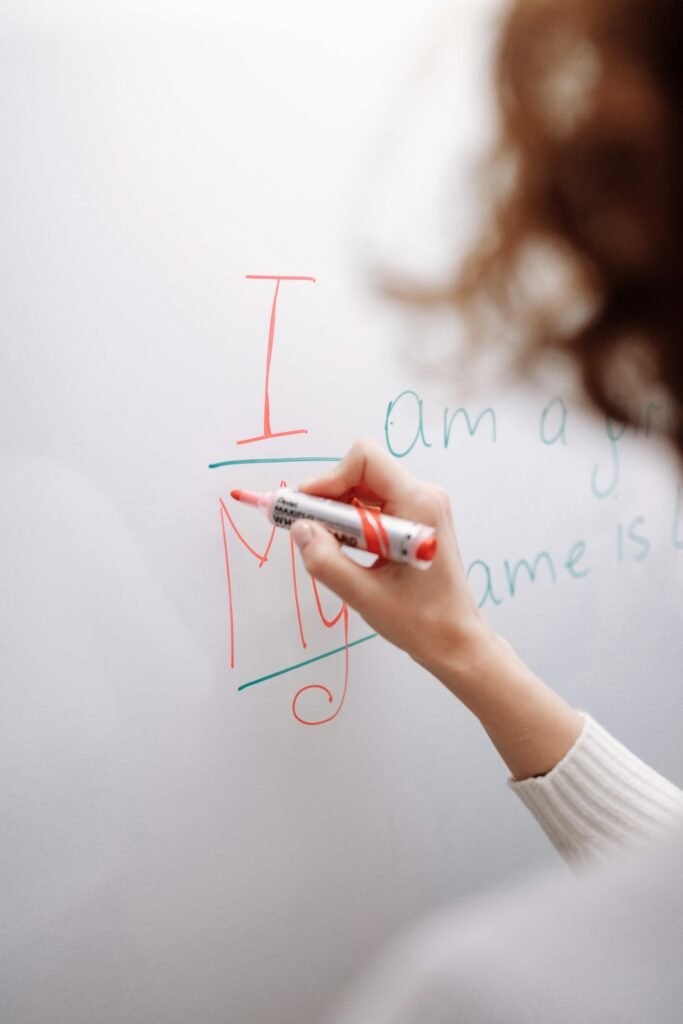 Mano de docente escribiendo estructuras gramaticales con un rotulador en una pizarra blanca durante una clase de inglés personalizada de MPC Languages